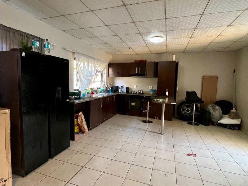 A dated kitchen featuring dark built-in cabinetry, integrated oven and hob, tiled flooring, and a drop ceiling, offering potential for modernization.