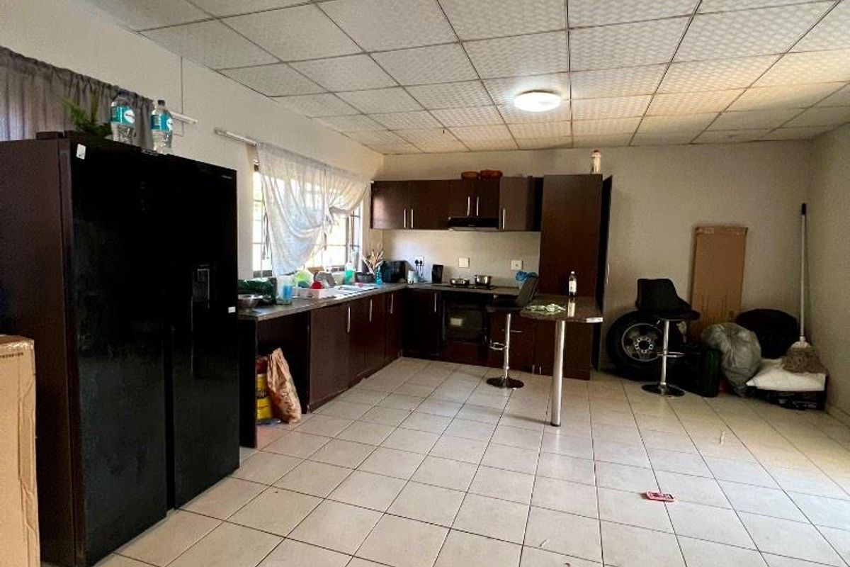 A dated kitchen featuring dark built-in cabinetry, integrated oven and hob, tiled flooring, and a drop ceiling, offering potential for modernization.