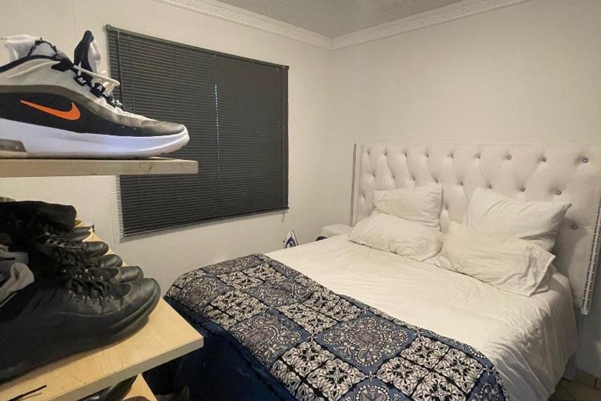 A bedroom featuring tiled flooring, a textured ceiling with crown molding, and a window fitted with a dark venetian blind.