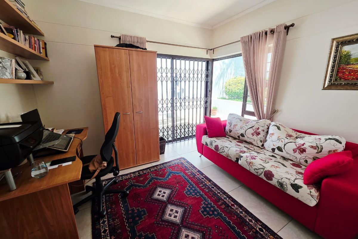 A functional bedroom featuring tiled flooring and a sliding glass door with a security gate, providing direct access to the outdoor area.