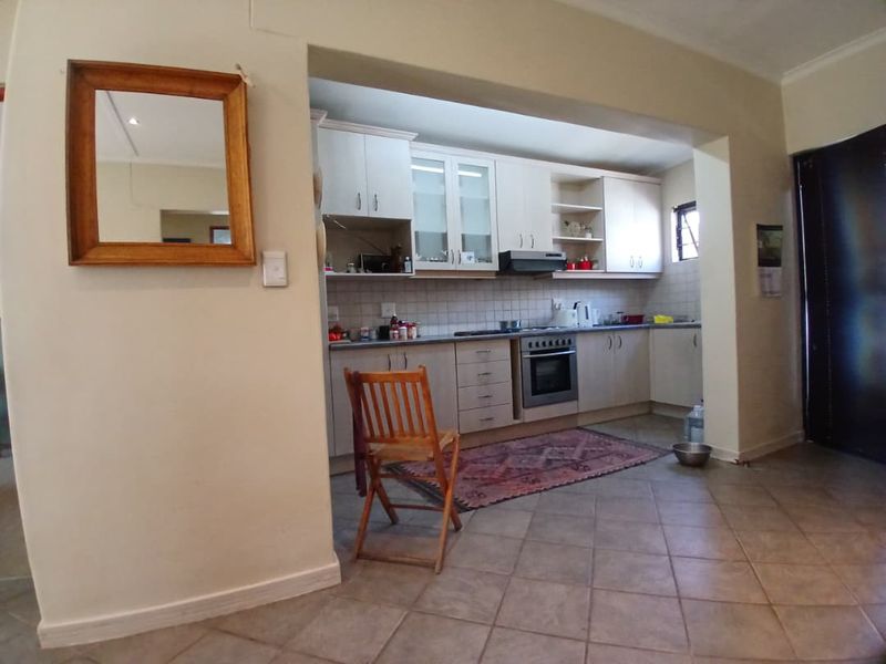 A functional kitchen featuring built-in cabinetry, tiled backsplash, and integrated oven with extractor fan, finished with tiled flooring.