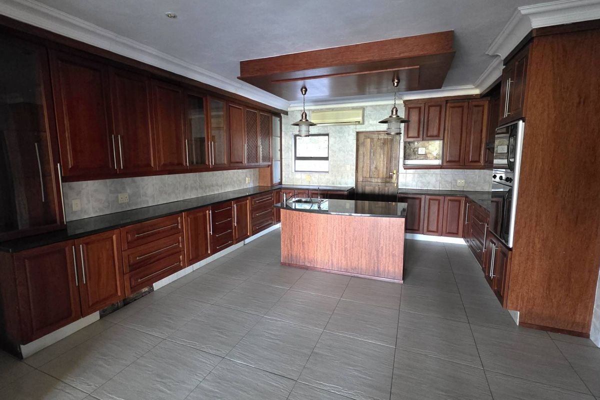 Spacious kitchen featuring extensive dark wood cabinetry, a central island, granite countertops, and integrated wall oven, offering ample storage and workspace.