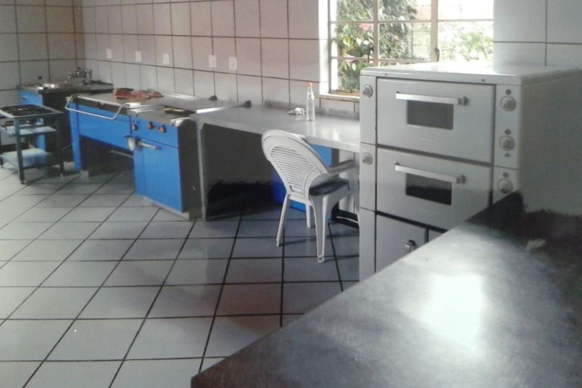 A functional commercial-style kitchen featuring tiled surfaces, stainless steel prep areas, and a built-in double oven unit.