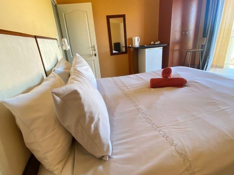 A hotel bedroom featuring tiled flooring, a split-system air conditioner, and a built-in wardrobe with access to an adjoining balcony.