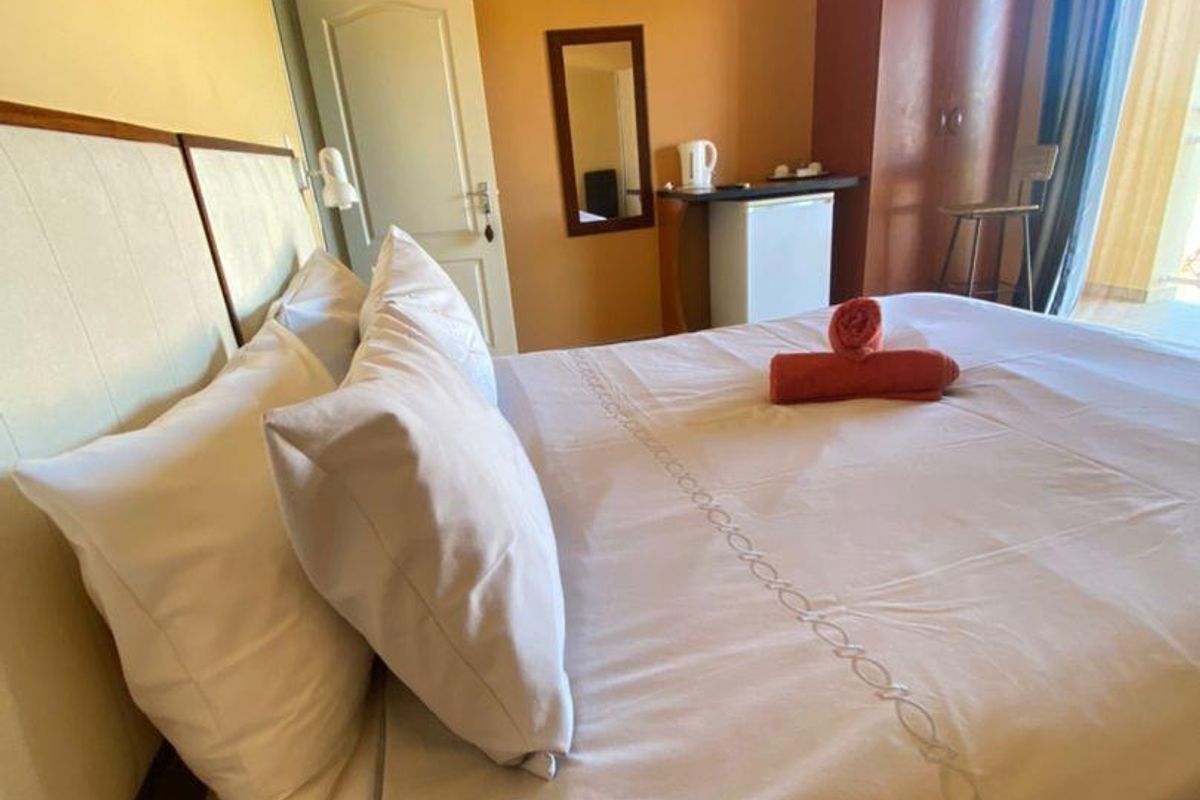A hotel bedroom featuring tiled flooring, a split-system air conditioner, and a built-in wardrobe with access to an adjoining balcony.