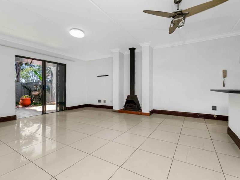 Spacious living area featuring neutral tiled flooring, a central freestanding fireplace, and sliding glass doors providing access to the outdoor patio.