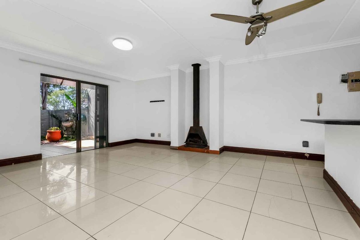 Spacious living area featuring neutral tiled flooring, a central freestanding fireplace, and sliding glass doors providing access to the outdoor patio.