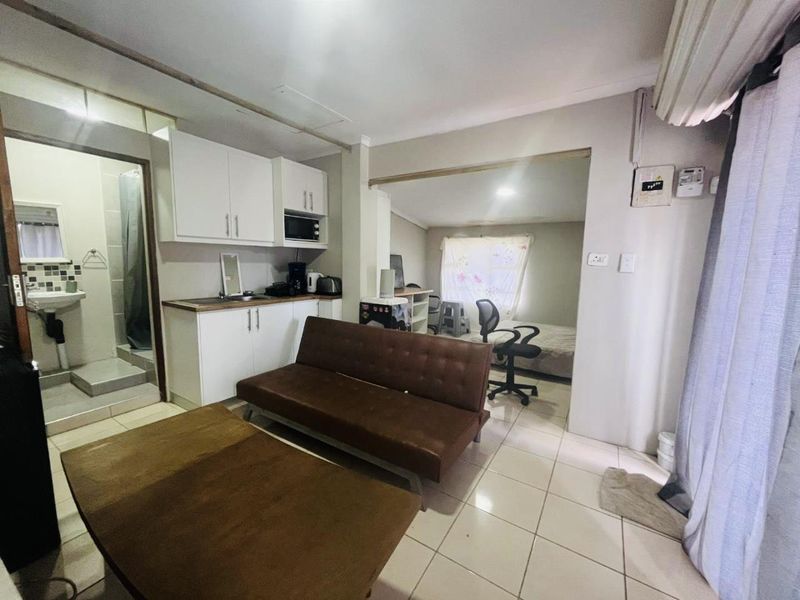 Open-plan living area featuring a compact kitchenette, tiled flooring, and an adjoining bathroom, offering a functional layout for a cottage-style property.