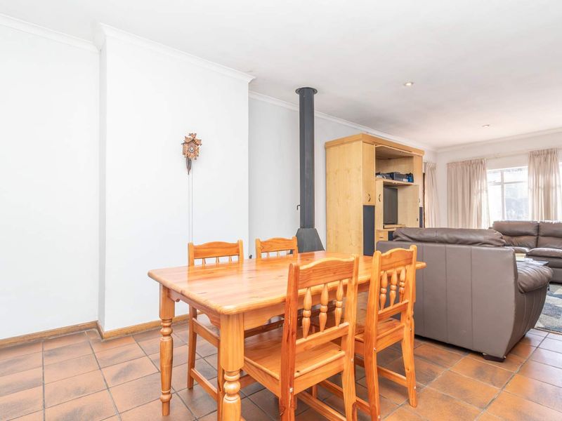 Open-plan living and dining area featuring tiled flooring and a central freestanding fireplace, creating a functional and connected living space.