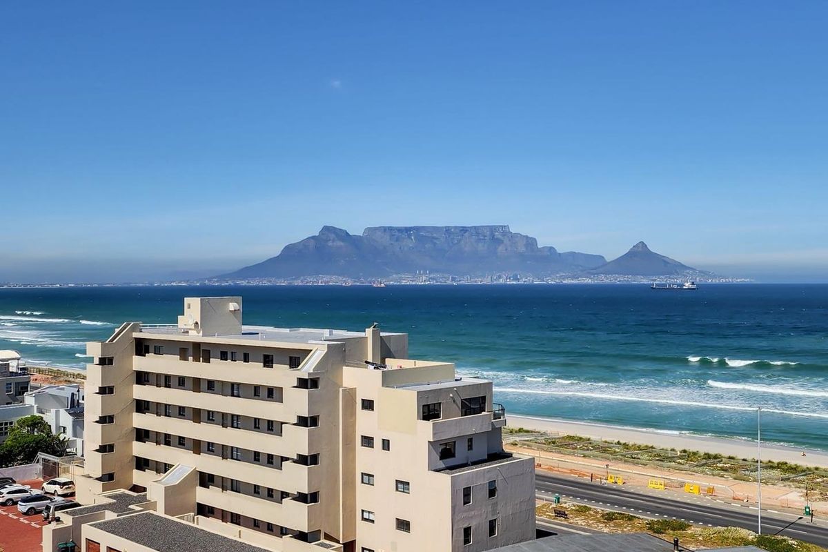 Elevated aerial view showcasing the apartment building exterior with a prominent, scenic outlook towards the ocean and Table Mountain.