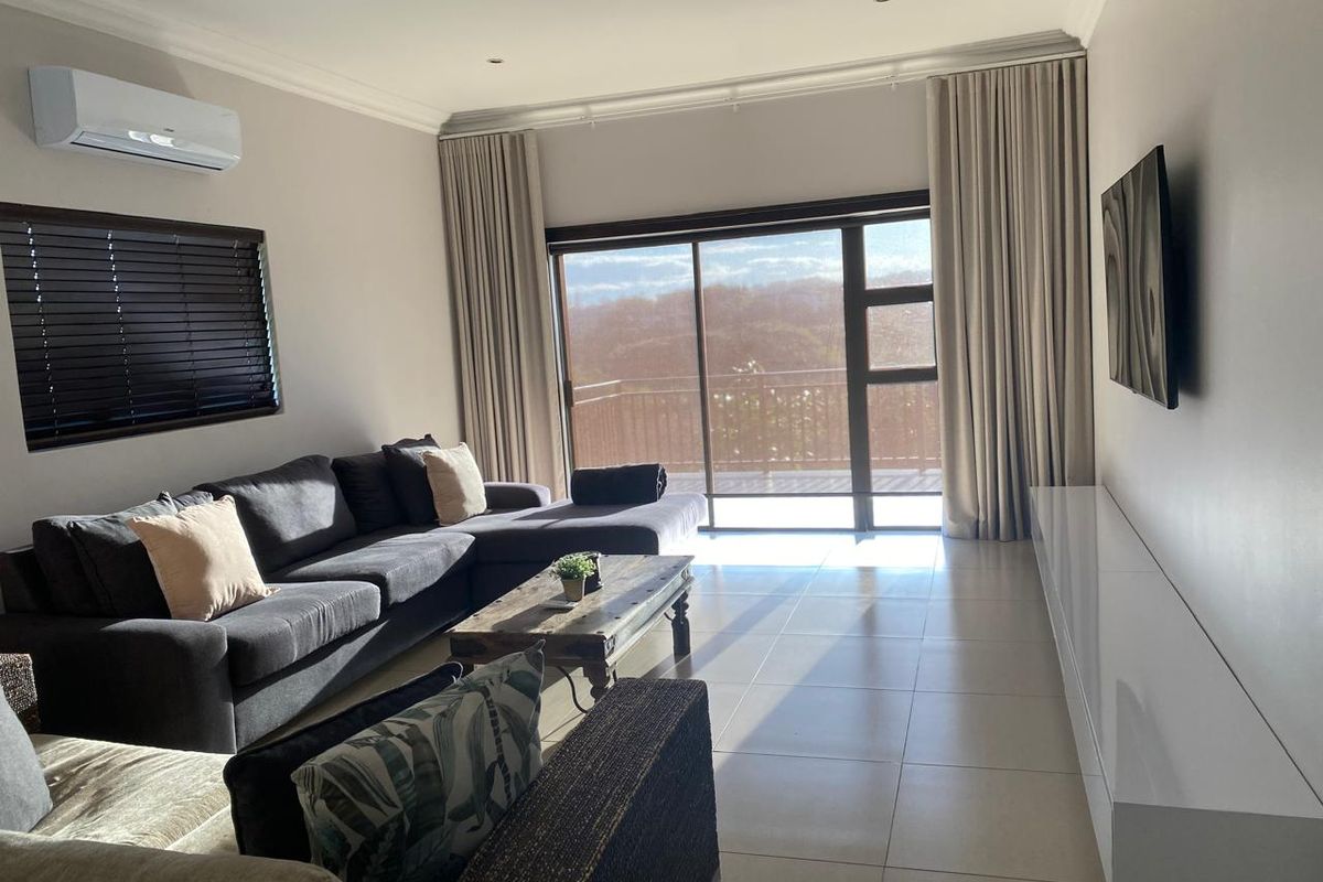 Spacious living room featuring tiled floors, recessed lighting, split-system air conditioning, and large sliding glass doors leading to an outdoor balcony.