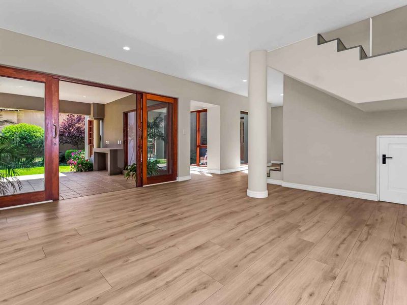 Spacious, light-filled living area featuring modern laminate flooring, recessed lighting, and large sliding doors providing seamless access to the outdoor patio.