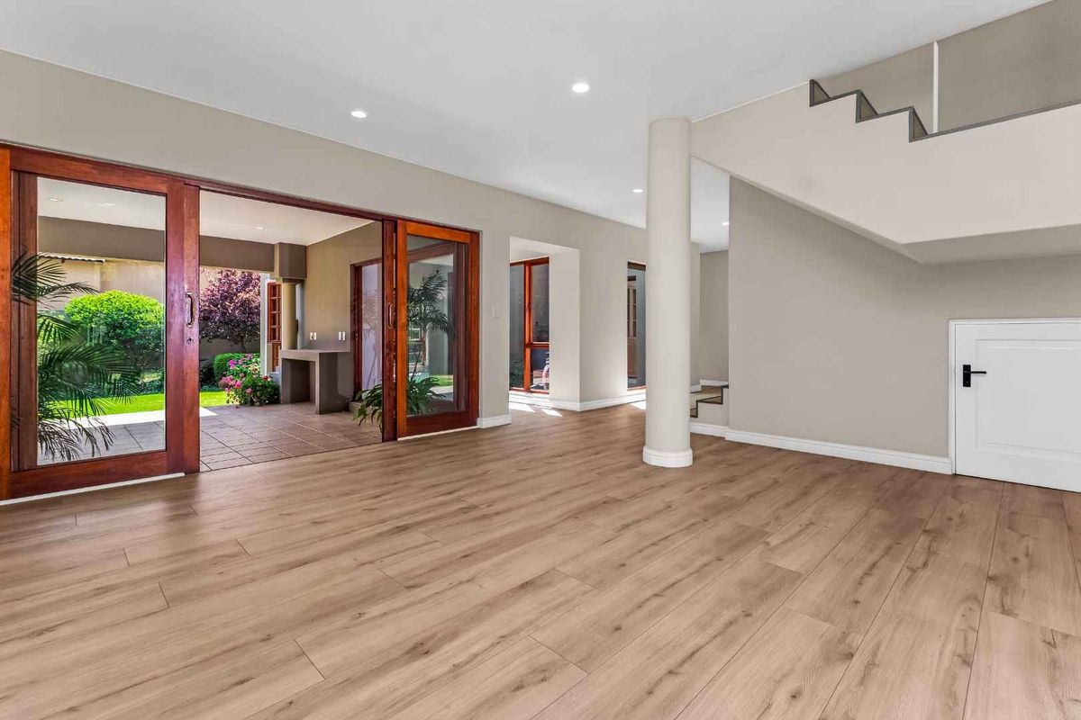 Spacious, light-filled living area featuring modern laminate flooring, recessed lighting, and large sliding doors providing seamless access to the outdoor patio.