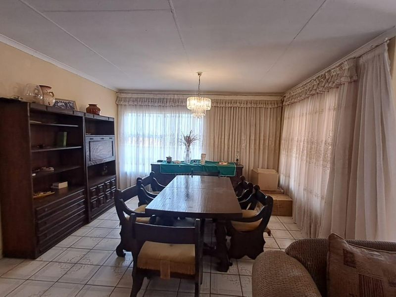 A dining room featuring tiled flooring and a central light fixture, currently showing signs of wear on the walls and ceiling.