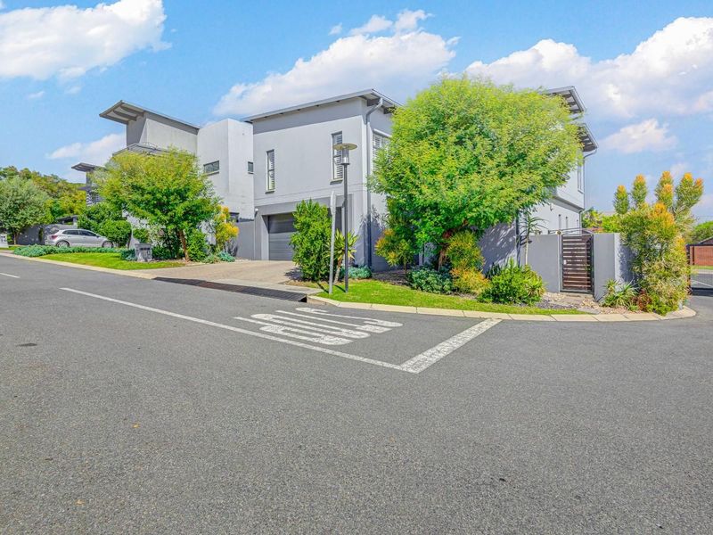 Street view of a modern multi-story residential property featuring a paved driveway, garage access, and landscaped front garden area.