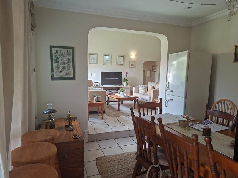 Open-plan living and dining area featuring tiled flooring, an arched transition between spaces, and recessed ceiling lighting.