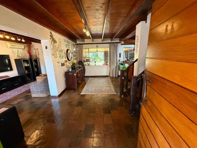Welcoming entrance hall featuring rustic slate tile flooring, exposed timber ceiling beams, and a solid timber front door leading into the main living area.
