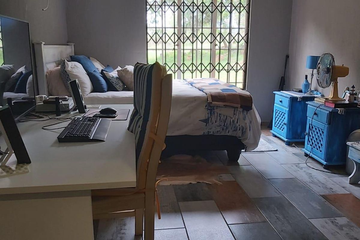 A functional bedroom featuring tiled flooring and a security gate on the window, providing a practical living space.
