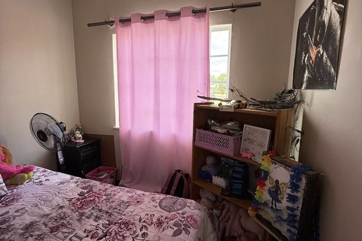 A standard bedroom featuring neutral wall paint, crown molding, and a window with a curtain rod.