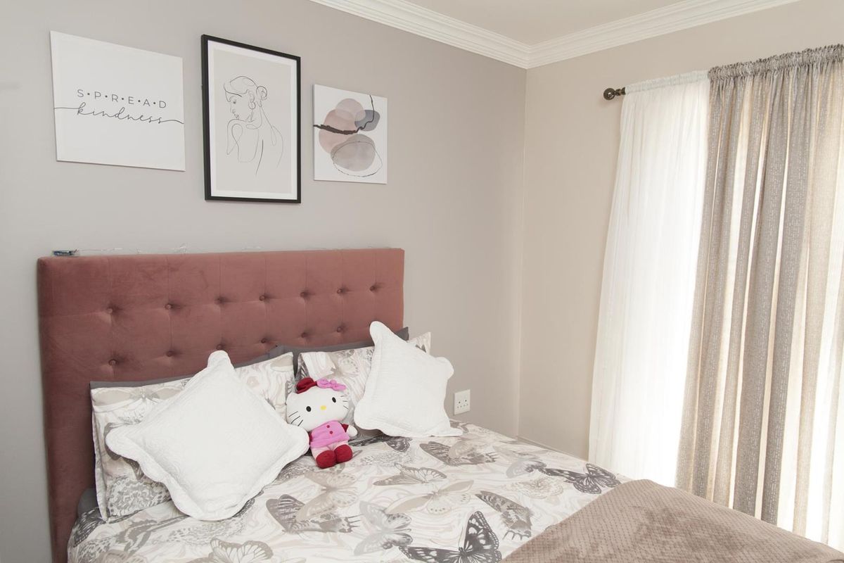 A well-maintained bedroom featuring neutral wall tones, crown molding, and a window with curtain tracks.