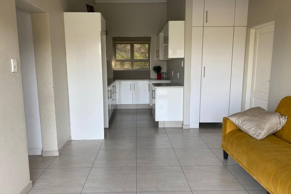 A functional kitchen featuring white built-in cabinetry, tiled flooring, and neutral wall finishes, providing a clean and practical workspace.