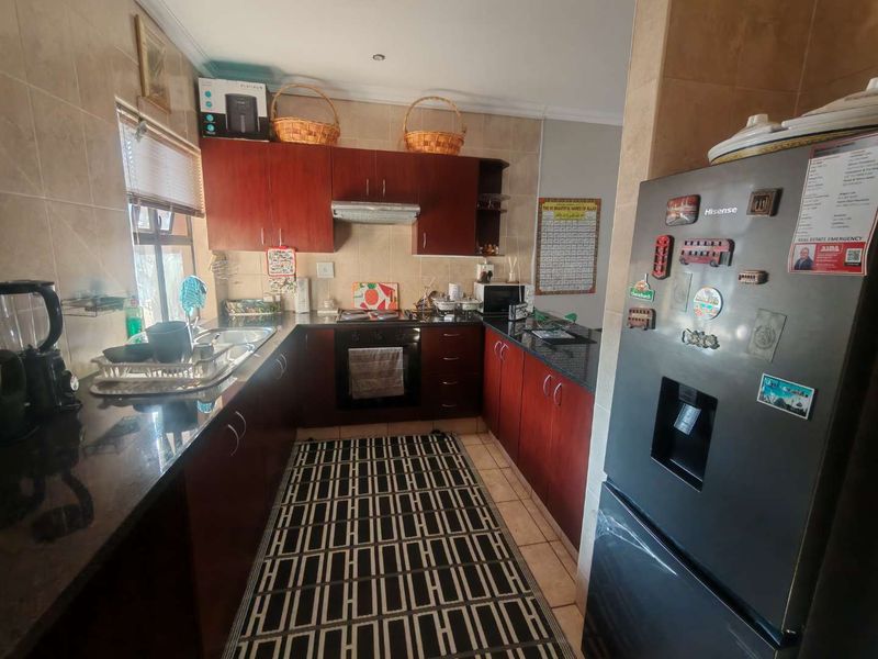 A functional kitchen featuring dark wood cabinetry, granite countertops, a built-in oven, and a tiled backsplash, offering a practical layout for daily cooking.