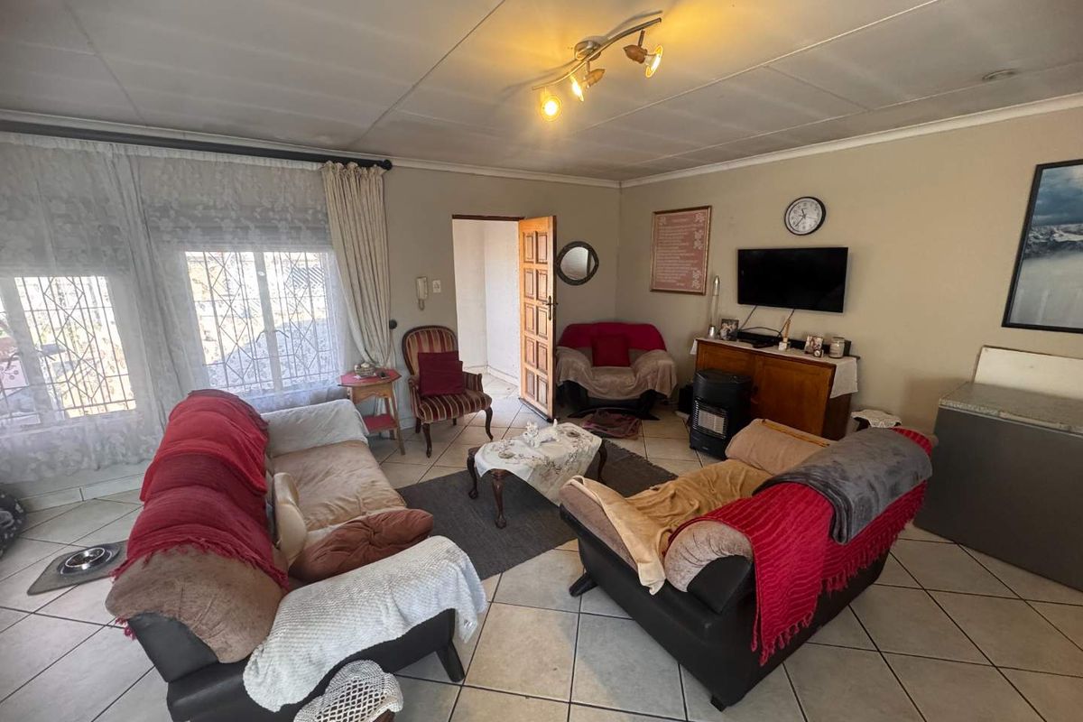 A living room featuring tiled flooring and security bars on the windows, offering a functional space with potential for cosmetic updates.