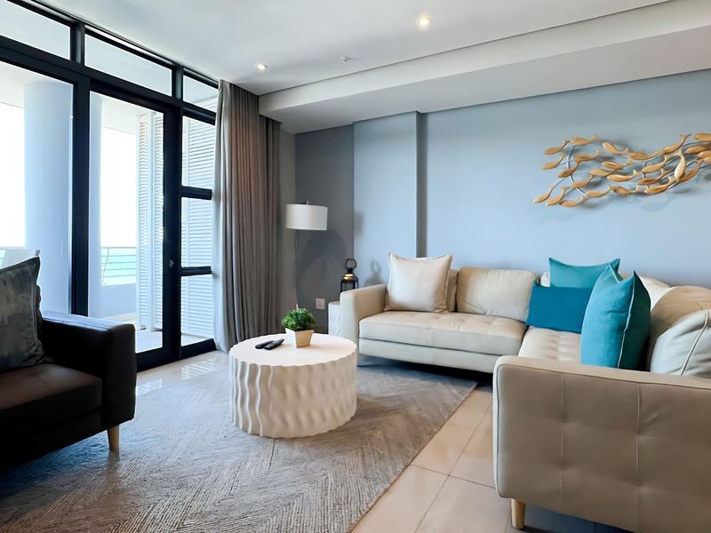 A bright and modern living room featuring tiled floors, recessed lighting, and large sliding glass doors providing access to an outdoor balcony area.