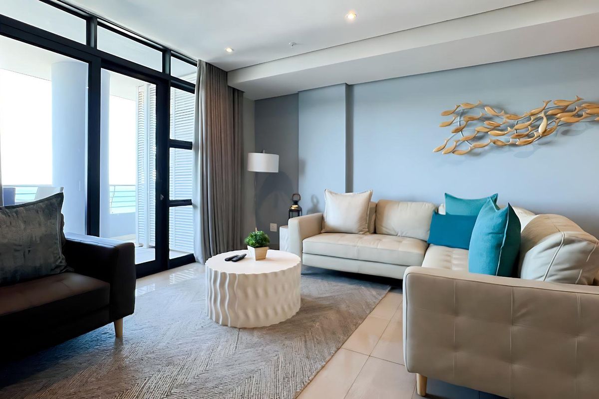A bright and modern living room featuring tiled floors, recessed lighting, and large sliding glass doors providing access to an outdoor balcony area.