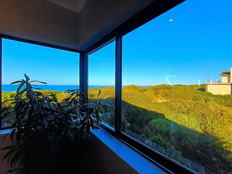 A bright interior space featuring a large corner window with expansive views of the surrounding coastal landscape and ocean.