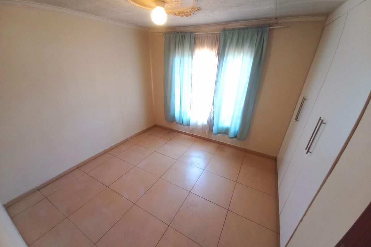 A simple bedroom featuring tiled flooring and built-in wardrobes, offering a functional space ready for personalization.