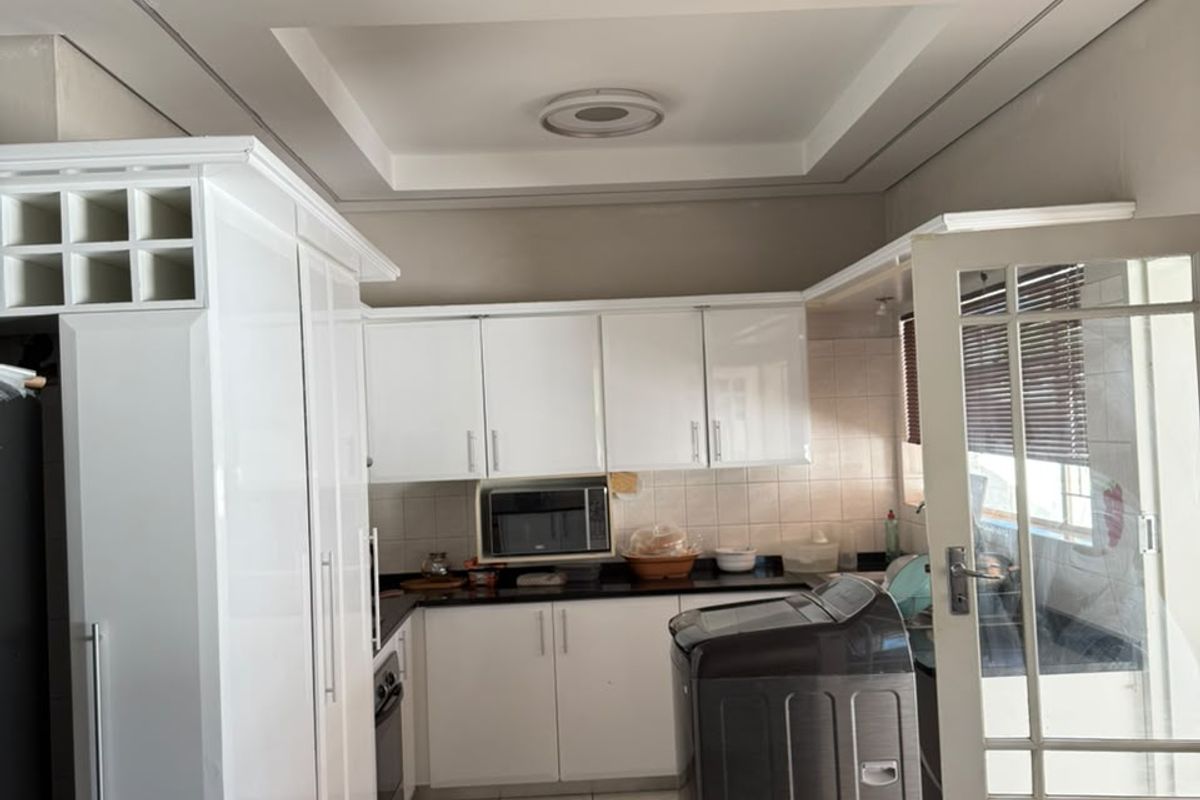 A functional kitchen featuring white cabinetry, granite countertops, built-in microwave, and a decorative tray ceiling with recessed lighting.