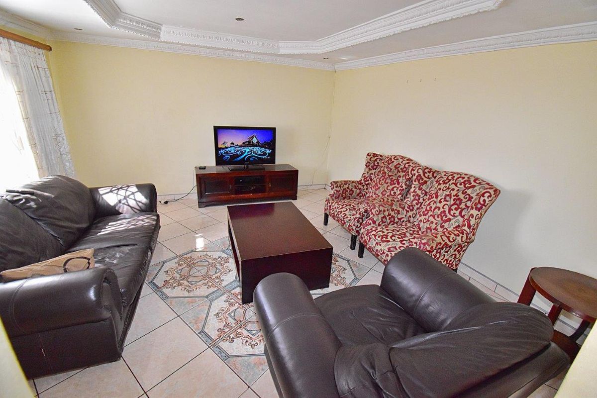 A living room featuring decorative ceiling cornices and tiled flooring with a central patterned inlay.