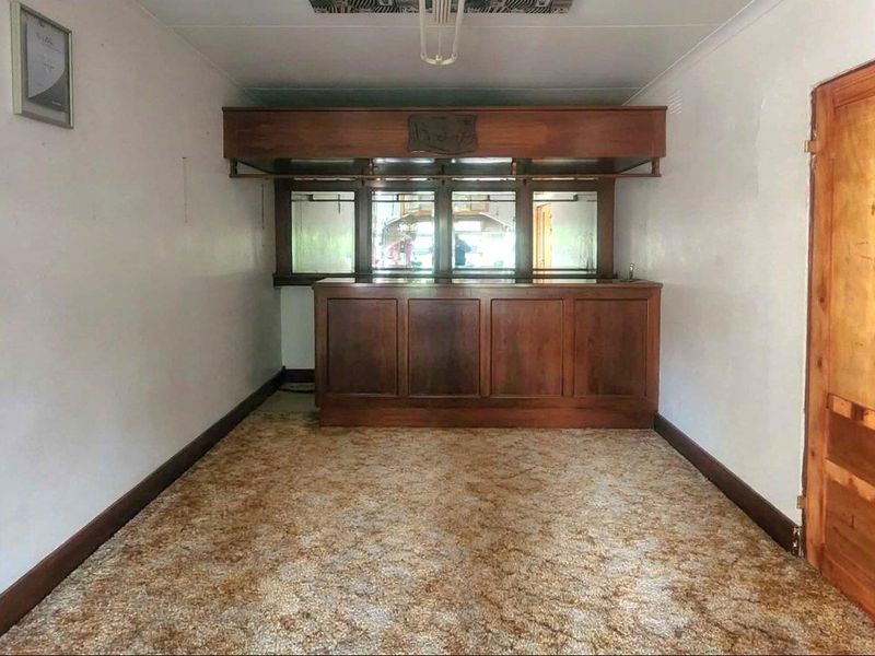 A dedicated bar area featuring a built-in wooden counter, mirrored back bar, and overhead canopy, offering potential for a modern entertainment space.