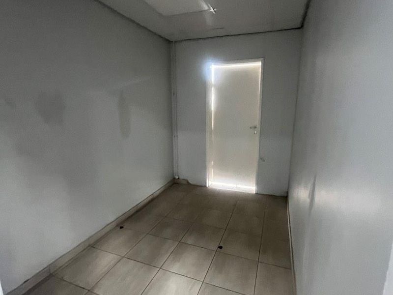 A vacant utility or storage room featuring tiled flooring and a drop ceiling, requiring cosmetic updates to improve its overall condition.