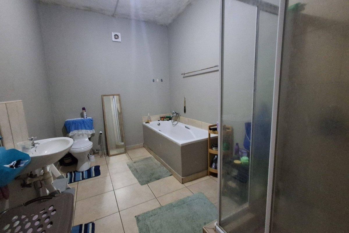 A functional bathroom featuring a built-in bathtub, separate shower enclosure, pedestal sink, and toilet, requiring cosmetic updates to the ceiling and finishes.
