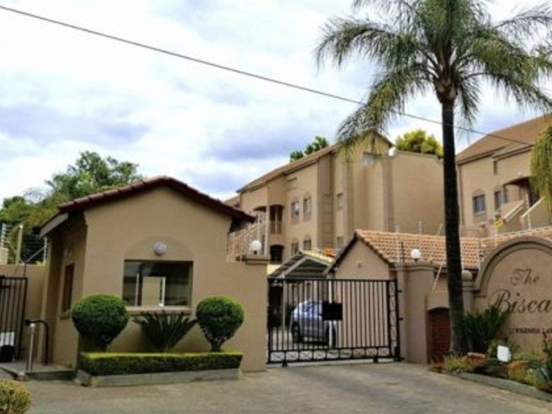 Front entrance view of The Biscays apartment complex, featuring a secure gated access point, guard house, and well-maintained exterior facade.