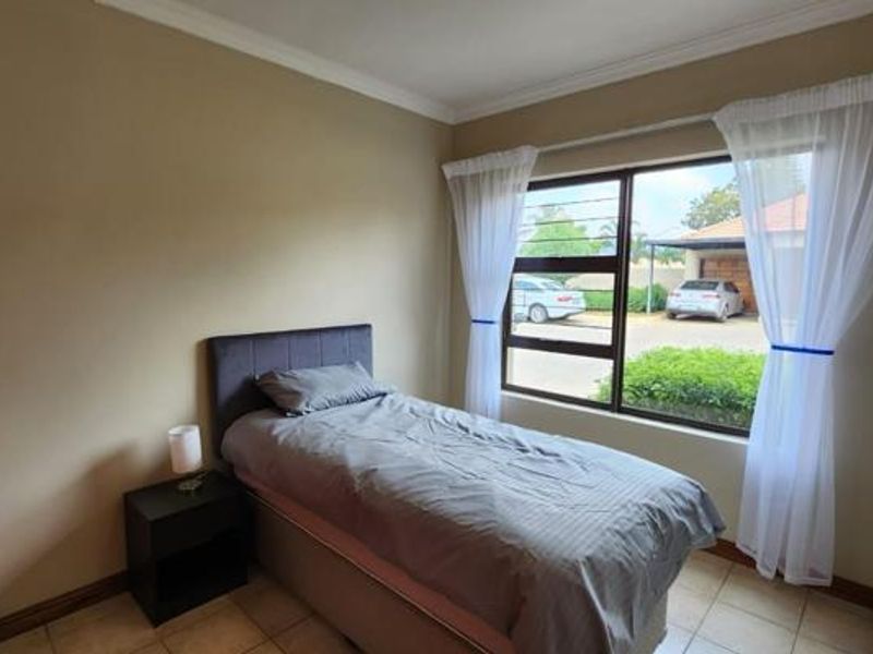 A bedroom featuring tiled flooring, large window with natural light, and neutral wall finishes.