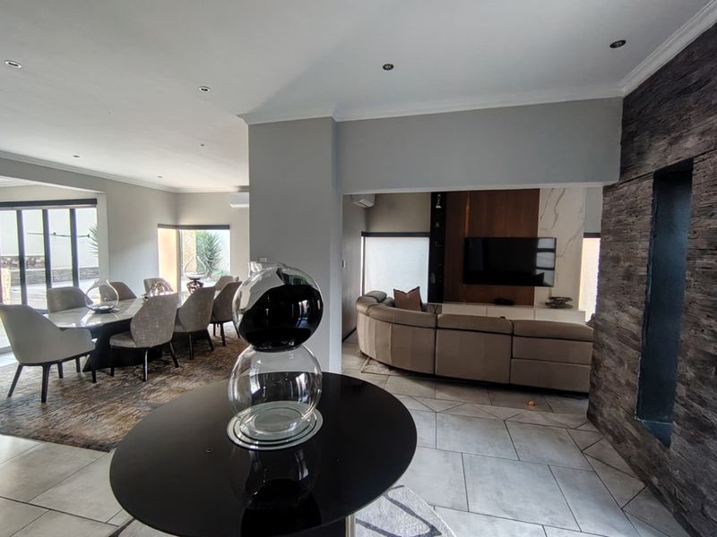 Spacious open-plan living and dining area featuring modern tiled floors, recessed lighting, and a striking stone feature wall with integrated media cabinetry.