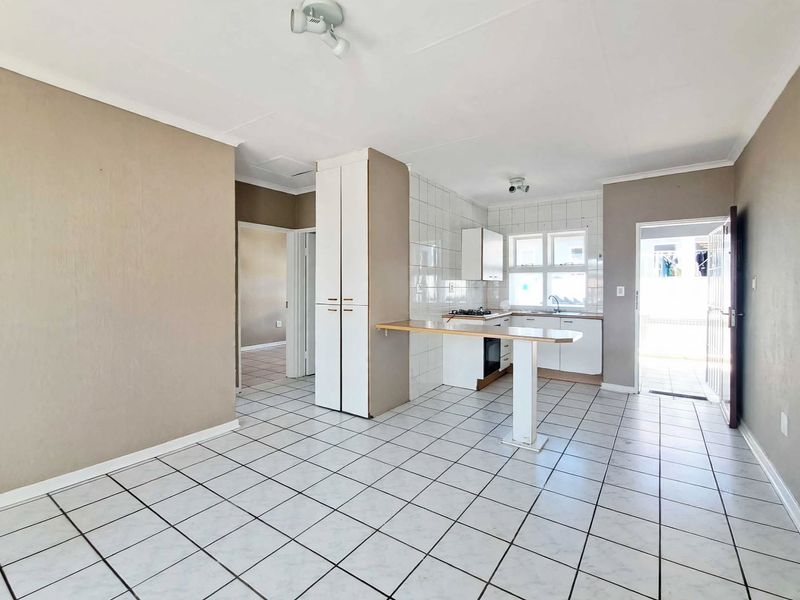 Open plan kitchen and living area featuring tiled flooring, built-in cabinetry, a breakfast bar, and direct access to an outdoor area.