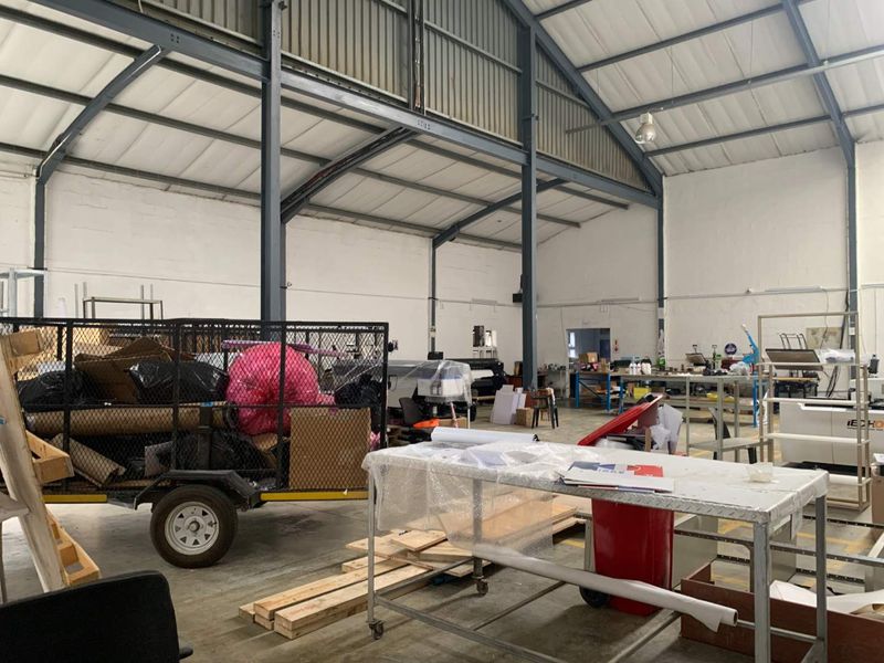 Spacious industrial warehouse unit featuring exposed steel portal frame construction, high-pitched metal roofing, and durable concrete flooring, suitable for various commercial or manufacturing operations.