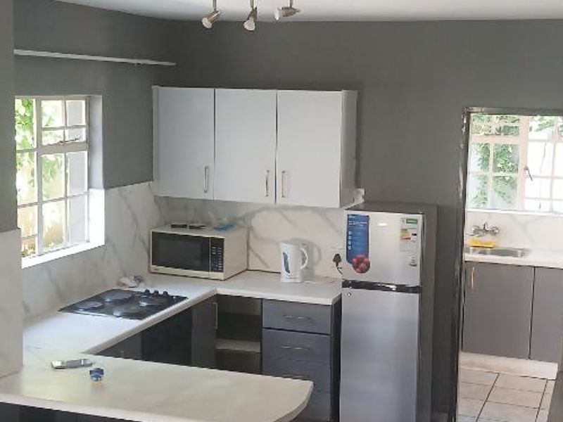Open plan kitchen featuring built-in cabinetry, a breakfast bar, and tiled flooring, with an adjacent scullery area visible.