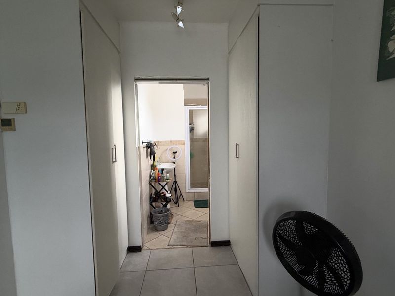 A functional hallway featuring built-in cupboards for storage, tiled flooring, and direct access to an adjoining bathroom.