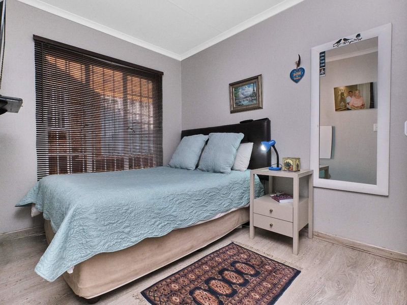 A cozy bedroom featuring light-toned laminate flooring, coved ceilings, and venetian blinds, providing a neutral foundation for personalization.