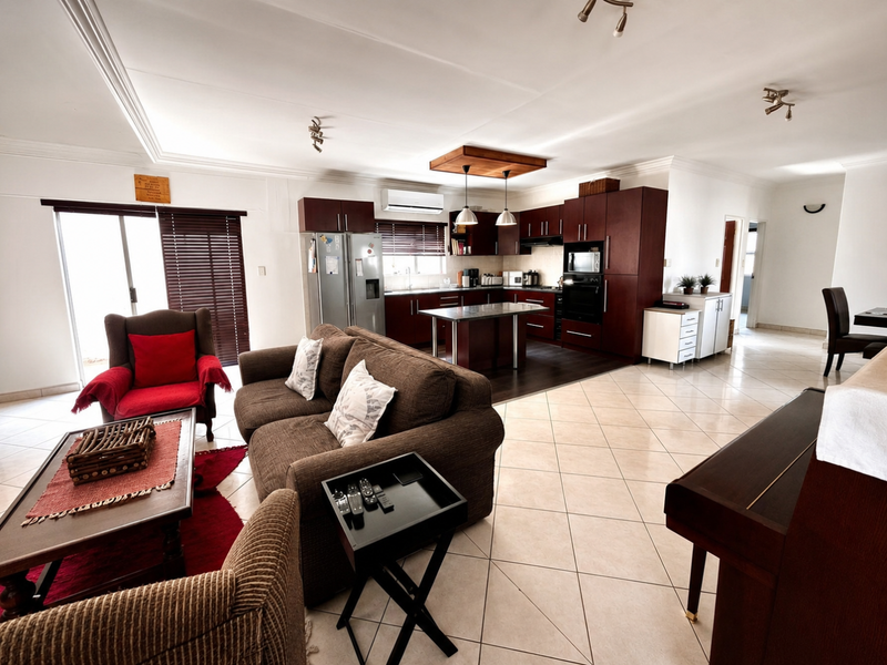 Spacious open-plan living area featuring a modern kitchen with dark wood cabinetry, a central island, and tiled flooring throughout.