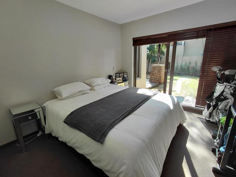 A bedroom featuring carpeted flooring and a sliding glass door providing direct access to the rear garden area.