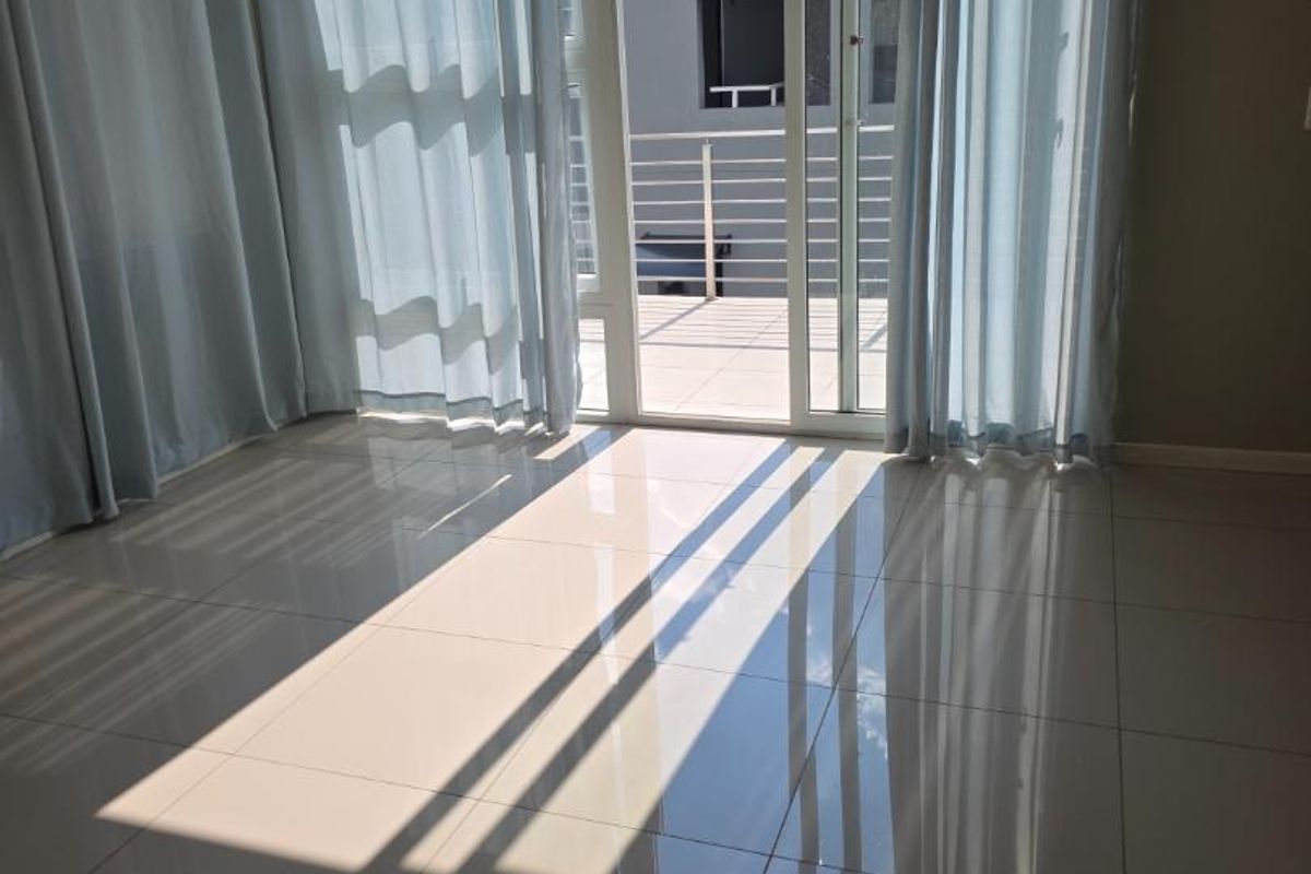 Bright and spacious living area featuring polished tile flooring and large sliding glass doors leading to an outdoor balcony.