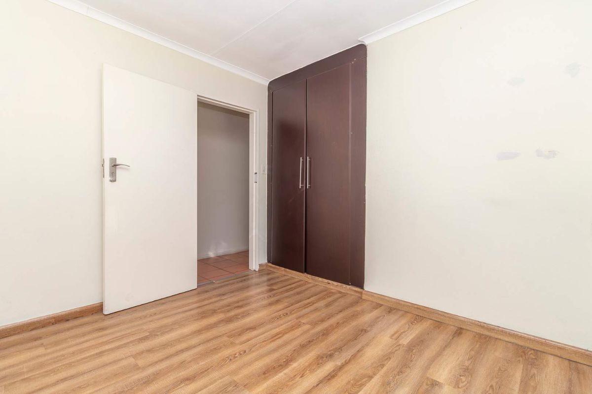 A vacant bedroom featuring laminate flooring and a built-in wardrobe, offering a neutral canvas for personalization.