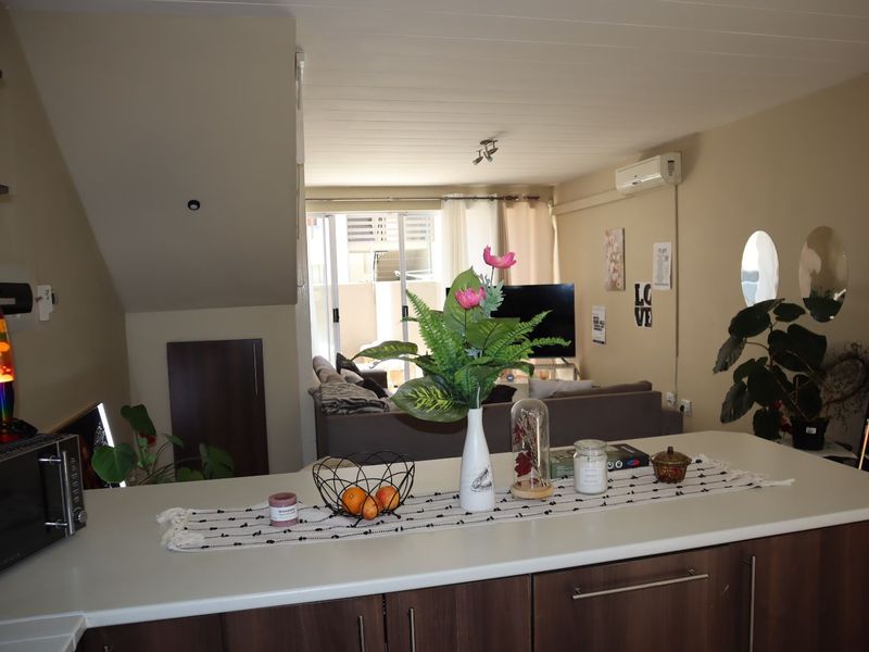 Open-plan living area featuring a kitchen island with cabinetry, flowing into a lounge space with sliding door access to the exterior.