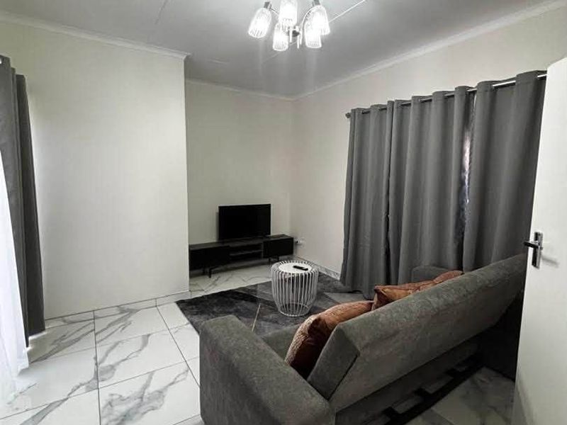 A bright living room featuring modern marble-look floor tiles, neutral walls, and a central ceiling light fixture.